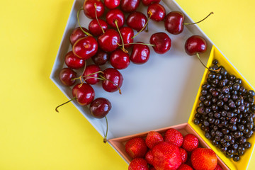 Cherries, strawberries, blue berries on yellow background. Colorful concept. Natural organic vegan healthy fresh food.