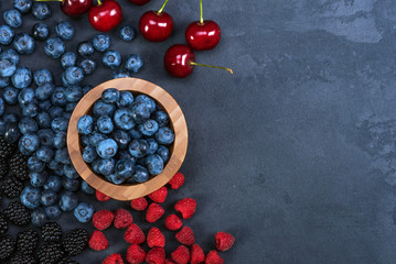Blackberries,blueberries,raspberries,cherries on black concrete background. Healthy food