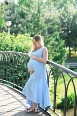Naklejka premium Beautiful portrait of a pregnant woman on a warm summer day in the nature. Pregnancy and season concept