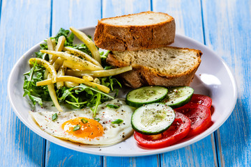 Breakfast - fried egg, toasts and vegetable salad