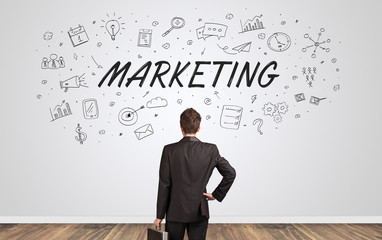 Young manager in doubt looking to a wall with business concept
