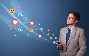 Young person using smartphone with flying social media icons around
