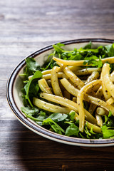 Yellow beans with arugula on wooden background