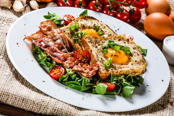 Breakfast - toasted bread with fried egg, bacon and vegetables