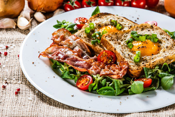 Breakfast - toasted bread with fried egg, bacon and vegetables