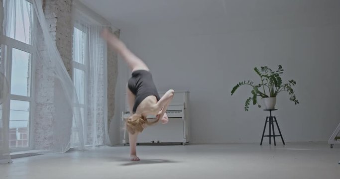Beautiful ballerina performs a complex acrobatic turn in the air without the support of hands - backflip, salto. Slow motion