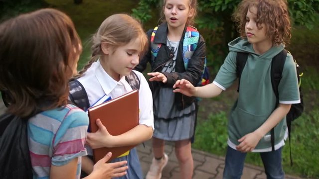 Bullying among adolescents and schoolchildren. Physical violence. A group of teenagers are pushing and insulting a schoolgirl. Adolescent violence problem