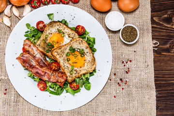 Breakfast - toasted bread with fried egg, bacon and vegetables