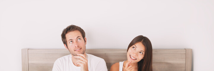 Couple thinking looking up at white copy space panoramic banner. Healthy relationship at home.