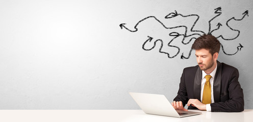 Businessman sitting at desk with direction concept
