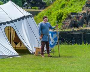 Medieval armorer stands by his shield.