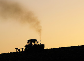 Fototapeta premium Tractor plowing the land at dawn