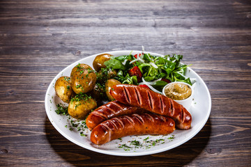 Grilled sausages, baked potatoes and vegetables