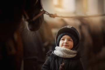 Teenage girl standing with horse in a stable