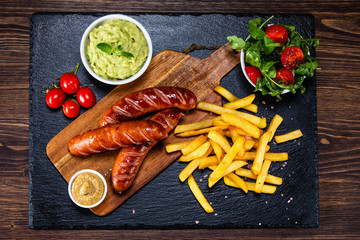 Grilled sausages, French fries and vegetables
