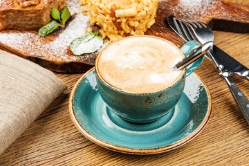 Cappuccino Cup with latte on wooden background. Beautiful foam, green ceramic Cup.
