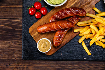 Grilled sausages, French fries and vegetables