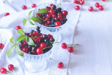 berries in glass bowls close-up. berry mix: cherry, black currant, red currant on the table.