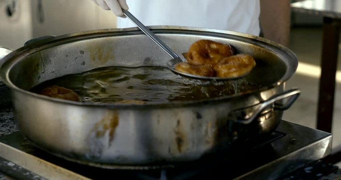 kitchener is deep-frying doughnuts, close-up of bowl with boiling oil