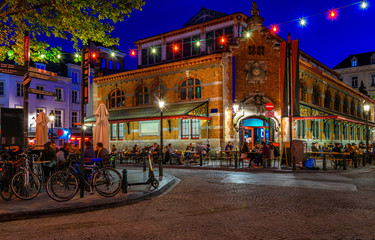Alte Straße mit Tischen des Cafés im Zentrum von Brüssel, Belgien. Nachtstadtbild von Brüssel (Bruxelles). Architektur und Wahrzeichen von Brüssel.