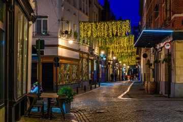 Old street with tables of cafe in center of Brussels, Belgium. Night cityscape of Brussels (Bruxelles). Architecture and landmarks of Brussels.