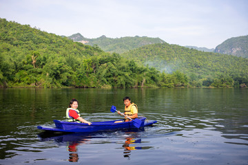Fototapeta na wymiar Asian couple rowing boat in river