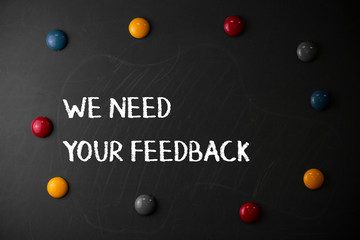 Text sign showing We Need Your Feedback. Business photo showcasing criticism given to say can be done improvement Round Flat shape stones with same sizes stick to old chalk black board