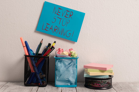 Conceptual hand writing showing Never Stop Learning. Concept meaning keep on studying gaining new knowledge or materials Blue Sticky Card on Wall Two Pencil Pots Mesh Paperclip Notes