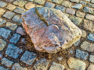 felsbrocken umrahmt von kleinen pflastersteinen