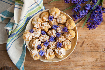 Homemade biscuit with violet hyacinth, white flower and yellow taraxacum on the wooden table