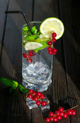 mojito with ice and red berries on a wooden background