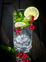 mojito with ice and red berries on a wooden background