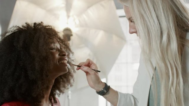Backstage of the Photo Shoot: Make-up Artist Applies lipstick Makeup on Beautiful Black Model, in a Moment Photographer Starts Taking Photos with Professional Camera Fashion Magazine Studio Photoshoot