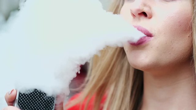 Stylish girl in a city. Lady use the electronic cigarette