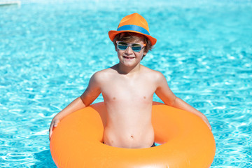 young child smiling in the pool with float and glasses