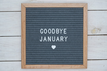 text in English goodbye January and a heart sign on a gray felt Board in a wooden frame