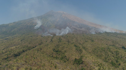 slopes volcano with forest fire, farmland at foot of the volcano Agung. tropical landscape aerial view mountains are covered with forest. Bali, Indonesia.
