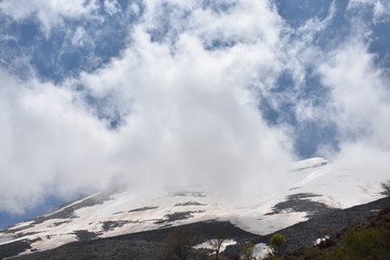 Fototapeta na wymiar clouds over snowy mountain summit
