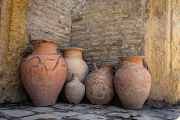 Ancient clay jars against a brick wall