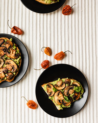 Avocado Toast with Mushrooms On A Black Plate with Light Background, Top View
