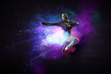Modern female dancer jumping in hoodie with colourful splashes background. Mixed media