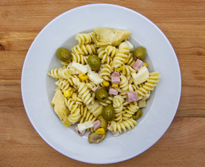 Cold summer salad, fusilli italian pasta on white plate, view from above