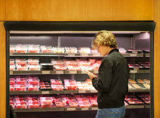 Teenager purchasing a packet of meat at the supermarket