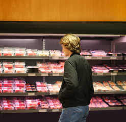Teenager purchasing a packet of meat at the supermarket