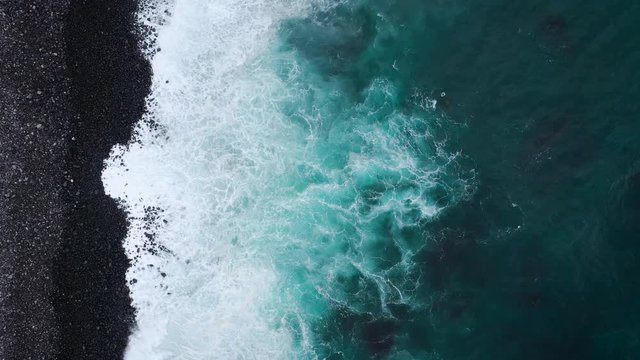 Top view of a deserted black volcanic beach. Coast of the island of Tenerife. Aerial drone footage of sea waves reaching shore