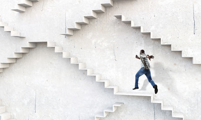 Black businessman climbing stone stairs illustrating career development and success concept. Mixed media