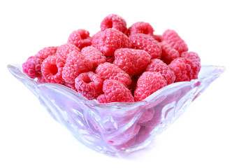 Glass bowl with sweet red raspberry on white background