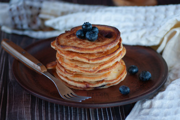 Pancakes with blueberry and honey. On a wooden table with a white towel