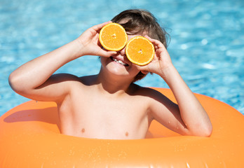 young child smiling in the pool with float and glasses