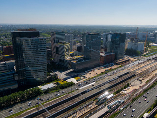 Fototapeta premium Aerial of modern office buildings on the Amsterdam Zuidas business district connected by highway and train station